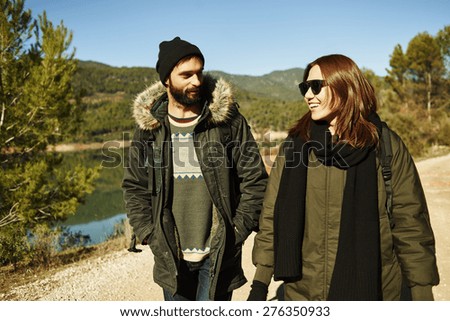 Happy couple in active lifestyle having fun on hike. Hikers walking in mountain forest during camping travel hike. Healthy lifestyle photo of Asian woman and Caucasian man.