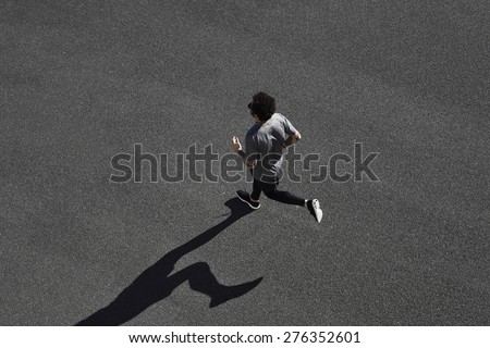 Top view athlete runner training at black road in sportswear at central position. Muscular fit sport model sprinter exercising sprint on city road. Full body length of Caucasian model.