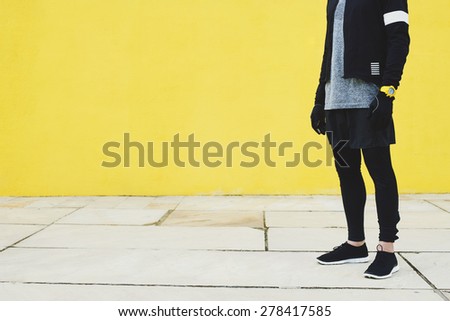 Tired sportsman after intensive jog athletic runner resting on yellow wall background at sunny day, attractive sporty man taking break after evening run, fitness and healthy lifestyle concept.