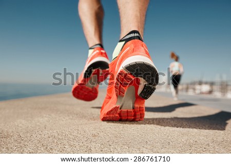 Close up runner feet. Man runner legs and shoes in action on road outdoors at road near sea. Male athlete model.