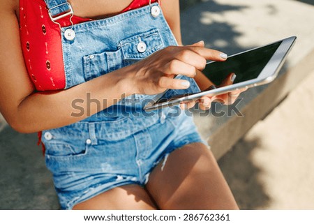 Close up portrait of young blonde girl working on her presentation on digital tablet, while sitting at park.