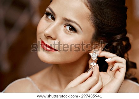 Woman putting on diamond earrings. Caucasian beauty lady trying and shopping jewelry.