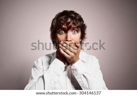 Closeup portrait of handsome young shocked business man, silent young business man covering closed mouth observing. Negative human emotion, facial expression sign symbol.
