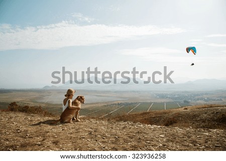 Beautiful girl with and dog on the mountain top.