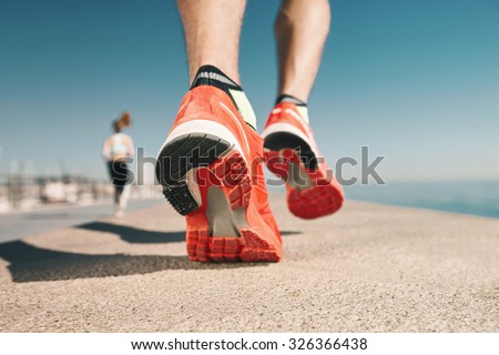 Running sport. Man runner legs and shoes in action on road outdoors at sunset. Male athlete model.