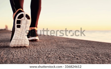 Runner man feet running on road closeup on shoe. Male fitness athlete jogger workout in wellness concept at sunrise. Sports healthy lifestyle concept