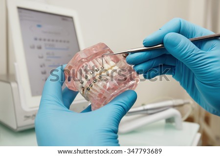 Prosthetics hands while working on the denture, false teeth, a study and a table with dental tools. Dental laboratory.