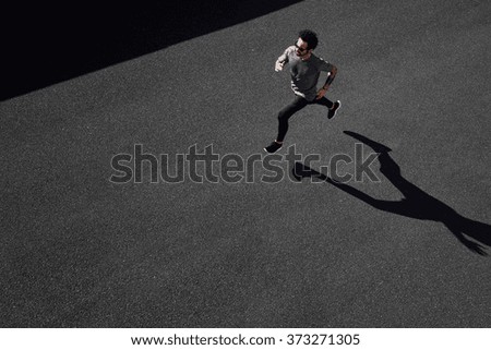 Man running on country road, healthy inspirational fitness lifestyle, sport motivation speed interval training. Runner jogging training and doing workout exercising power walking outdoors in city.