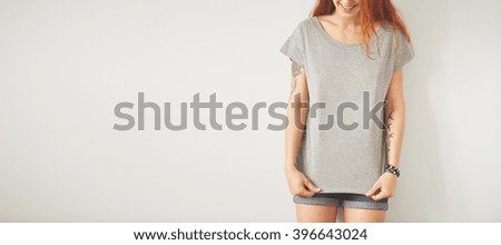 Young girl wearing grey blank t-shirt and blue jeans shorts. Concrete wall background with copy space for your text message or promotional content