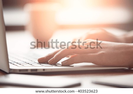 Cropped view of a female office worker relaxing in cafÃÂ© after busy working day. Close-up of busy female hand typing on keyboard while sitting at her working place in the office