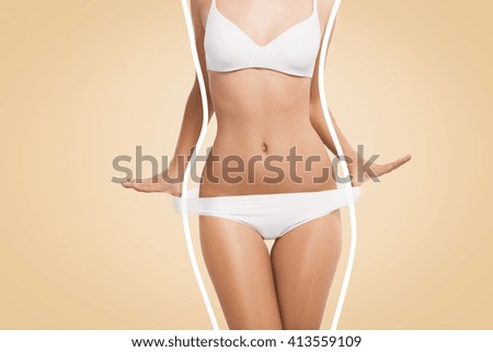 Cropped shot of slim and fit female model in white lingerie posing isolated against blank studio wall background. Close up portrait of attractive girl with perfect body wearing white bra and panties