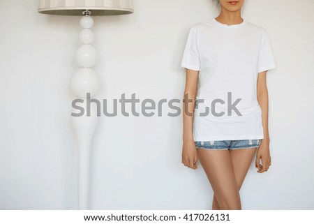Cropped isolated view of young casual woman. Female teenager posing in new clothes against white studio wall. Close up of fit woman in white blank T-shirt for your text message or advertising content