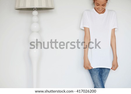 Human face expressions and emotions. Cropped portrait of attractive young female with happy smile posing in white blank copy space T-shirt for your advertising content against white studio wall.