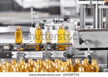 Factory process of production new cosmetics. Glass bottles standing on conveyor line going to be twisted. Automated process on big factory. Production of new shampoo on coveyor belt.Innovation concept