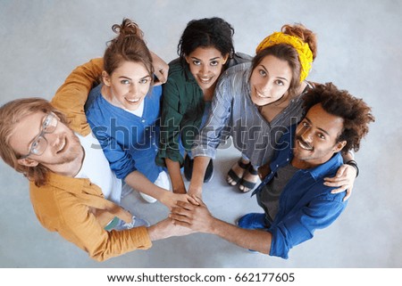 Friendly people of different races looking from above holding their hands together embracing each other rejoicing their victory. Diversity, teamwork, cooperation, ethnicity and people concept