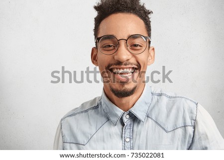 Positive emotions, facial expressions and happiness concept. Joyful man with oval face, mustache and beard smiles broadly, shows white perfect teeth, hears funny story or anecdote told by best friend