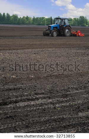 Tractor cultivating potato field (vertical view)