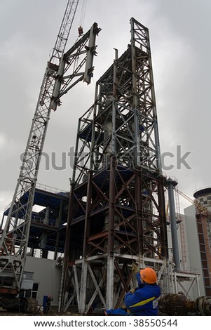 Worker directing a frame. Construction of chemical plant (urea producing)
