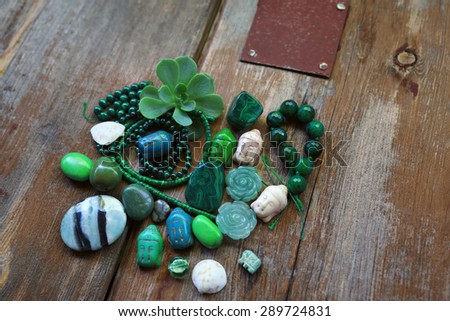 Abstract gemstone composition from turquoise crystals stone buddha head and loose jewelry beads next to white placeholder sheet of paper, succulent green plant flower over old vintage brown wood