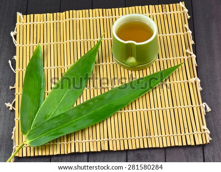 Tea time and Bamboo - Tea in Bamboo cup (on top right corner) on Bamboo mat and 3 Bamboo leafs
