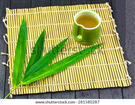 Tea time and Bamboo - Tea in Bamboo cup (on top right corner) on Bamboo mat and 4 Bamboo leafs