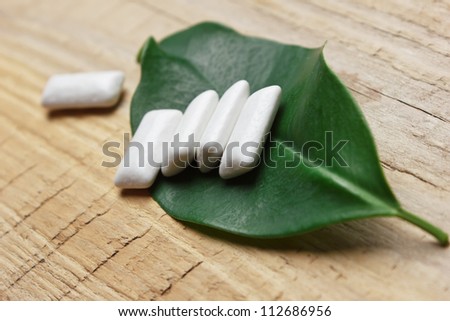 chewing gum and green leaf on a wooden background