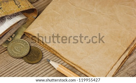 Old notes and coins and pencil on a wooden table