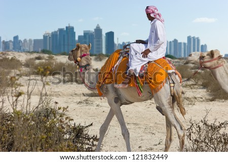 Bedouin on a camel in the desert and a modern city on the horizon Bedouin on a camel in the desert and a modern city on the horizon