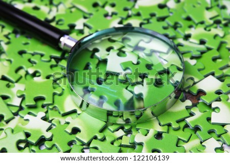 magnifying glass on pile of green puzzle magnifying glass on pile of green puzzle