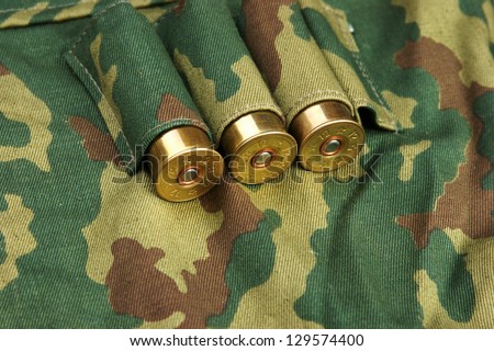 Old hunting cartridges and bandoleer on camouflage background