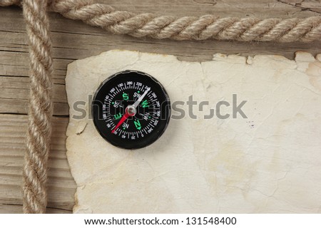 Vintage paper with compass and rope on old wooden boards