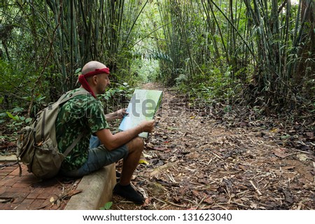Travelling man sitting and looking at the map in the bamboo forest