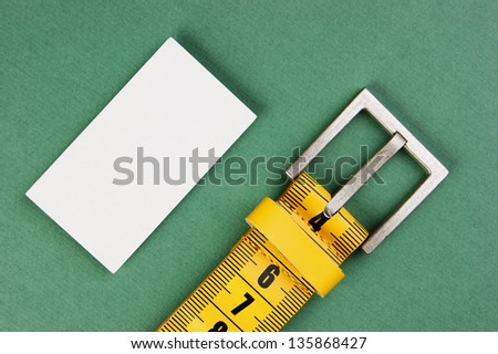 meter belt slimming and blank business card on the green background