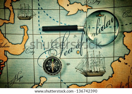 Old magnifier and compass on a stylized map