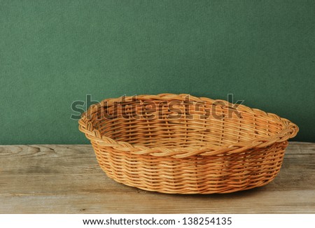 empty wicker basket on an old wooden table  against grunge wall