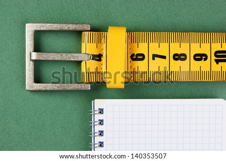 meter belt slimming and notepad on the green background