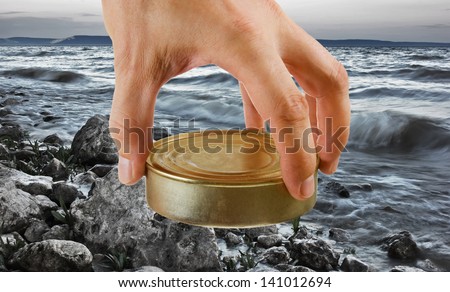 Food can in hand on a background of the sea