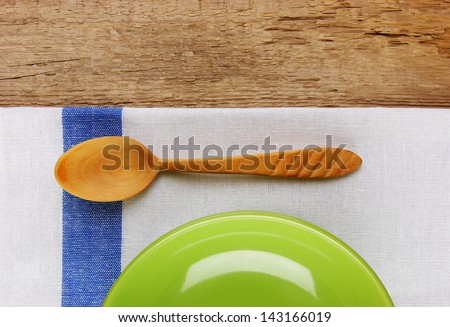 wooden spoon with a plate on the table cloth on an old wooden table