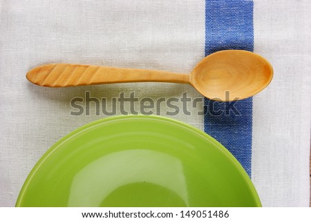 wooden spoon with a plate on the table cloth on an old wooden table