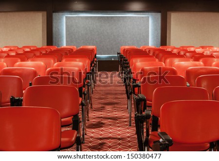 red recliners stand rows in an empty conference hall