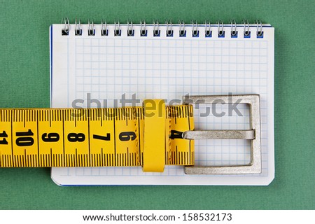 meter belt slimming and notepad on the green background