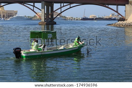 SHARJAH, UAE - OCTOBER 28, 2013: Workers in uniform on the boat cleaning bay.