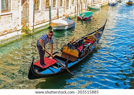 VENICE, ITALY - 26 JUNE, 2014: Gondolier rides gondola. The profession of gondolier is controlled by a guild, which issues a limited number of licenses