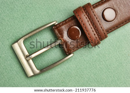 leather belt with a buckle on a green background