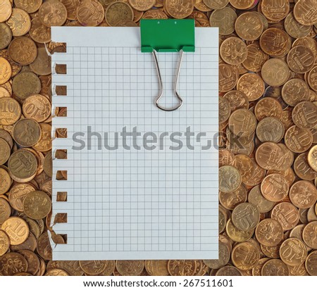 Blank page with paper clips on a pile of coins