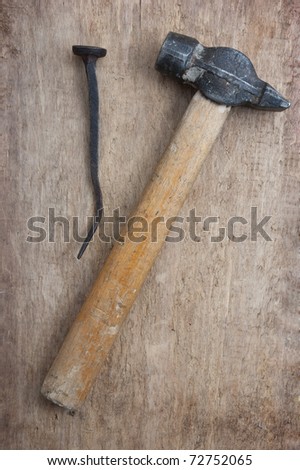 old hammer and a rusty nail on a blackboard