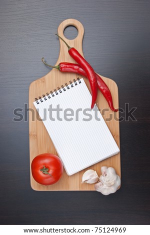 notebook for cooking recipes and red chili peppers on the kitchen table