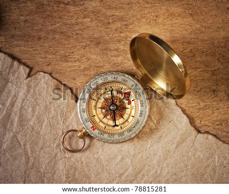compass and a piece of old paper on a wooden board
