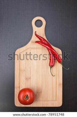 Red chili peppers and tomato on a cutting board