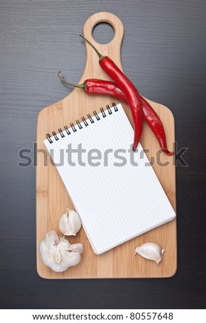 notebook for cooking recipes and red chili peppers on the kitchen table
